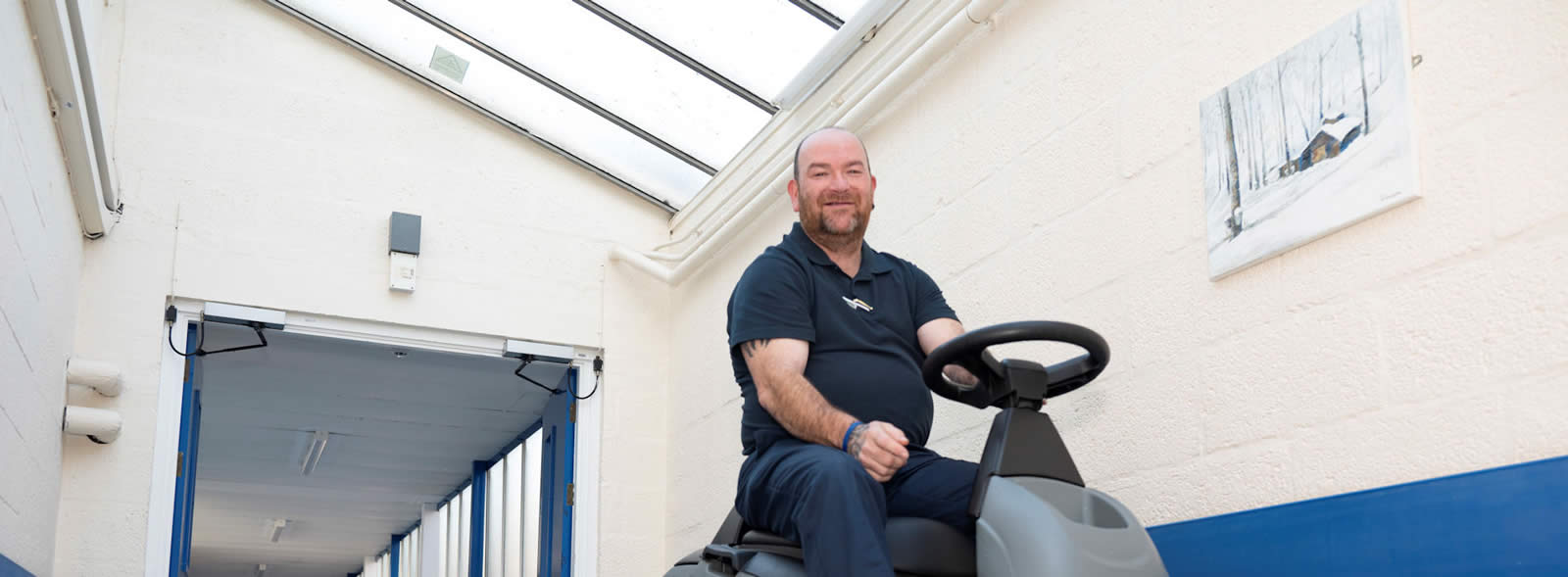 A man driving a floor cleaning machine in a hospital corridor