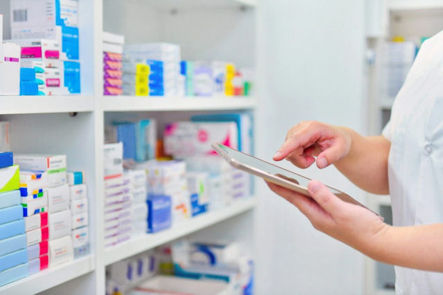 Shelves of medicines, hands holding tablet